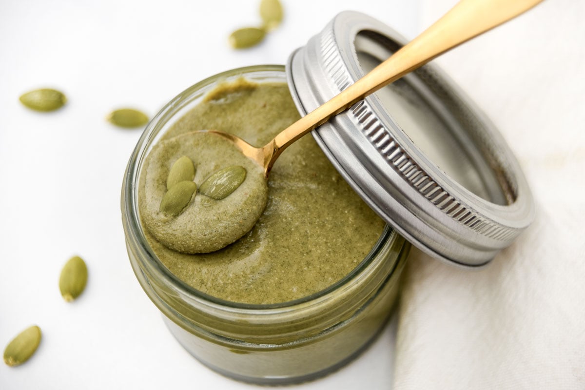 Homemade pumpkin seed butter and a spoon in a mason jar.