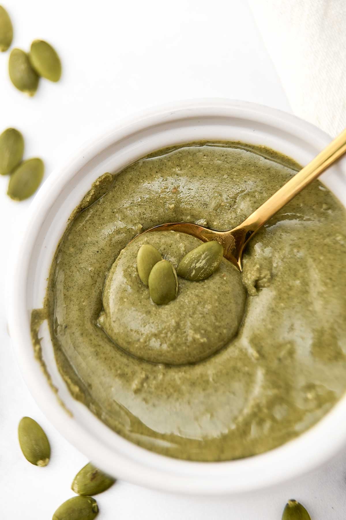 Homemade pumpkin seed butter made for dogs and a spoon in a small bowl.