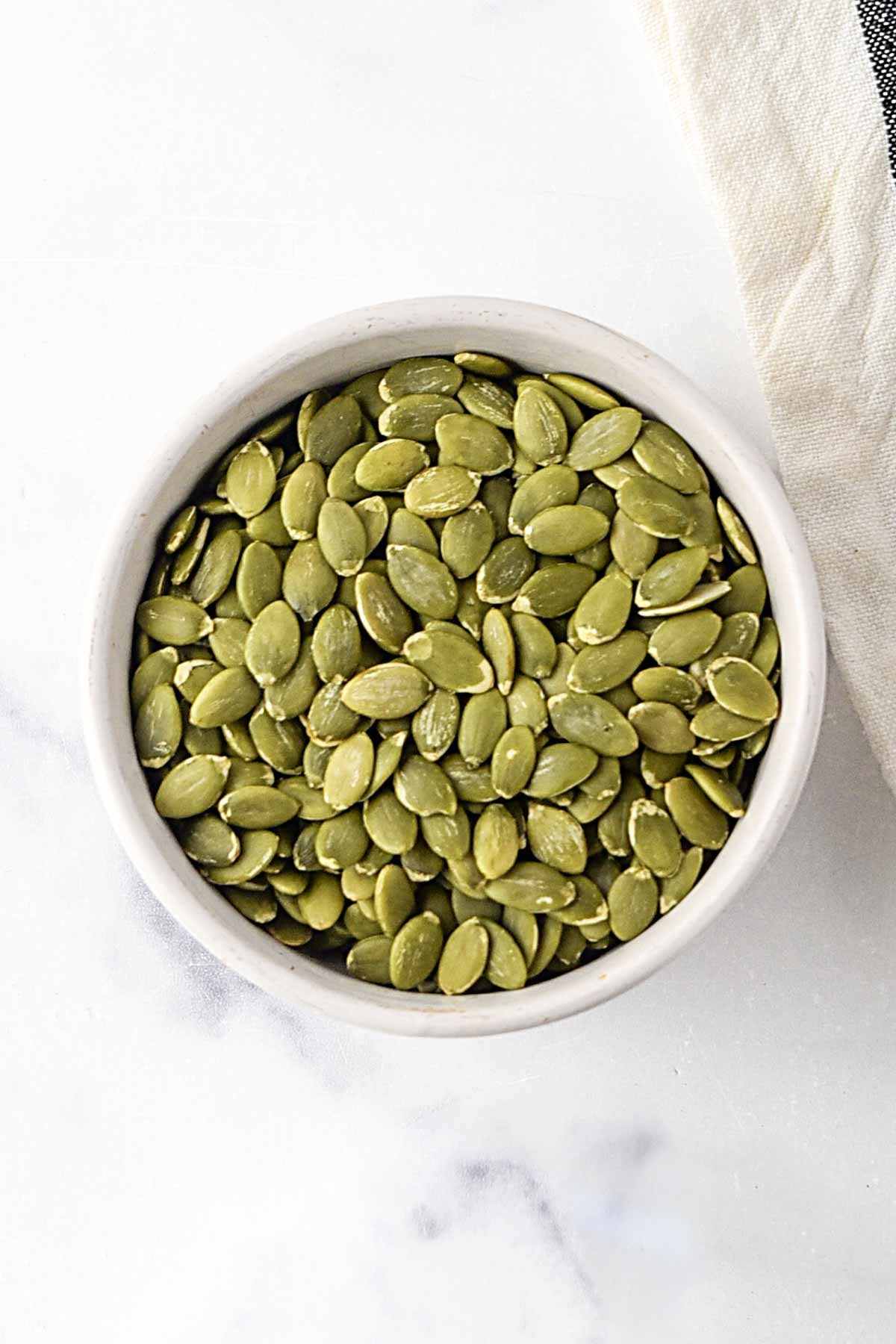 Raw pumpkin seed kernels in a bowl.